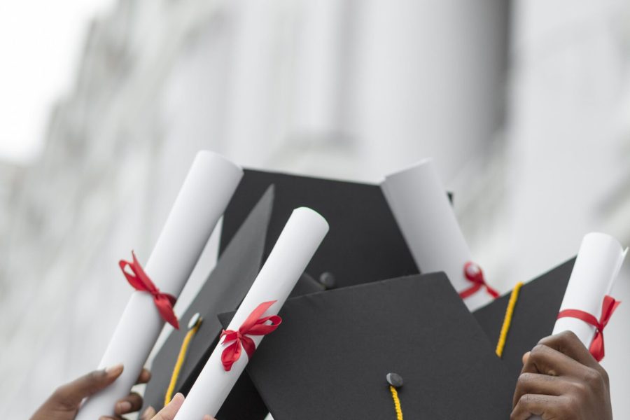 close-up-hands-holding-diplomas-caps close-up-hands-holding-diplomas-caps
